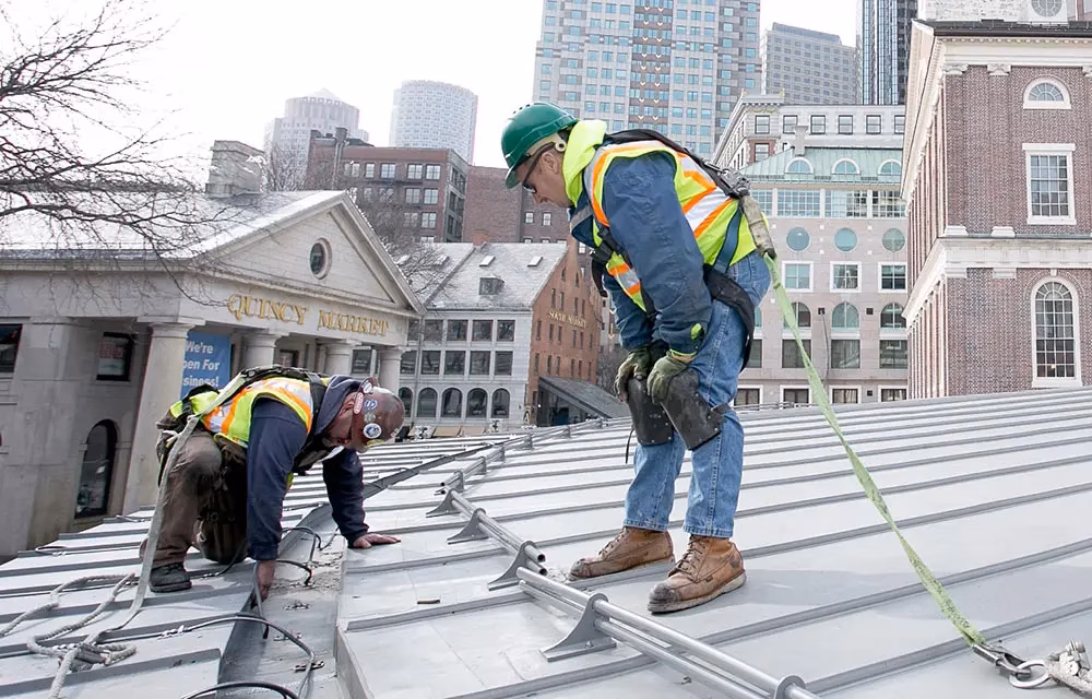 Two men repairing commercial roof safely.